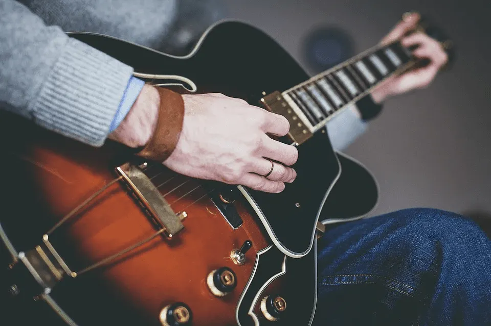 Strumming an electric guitar, close-up shot of musician's hand and fretboard in a cozy setting.