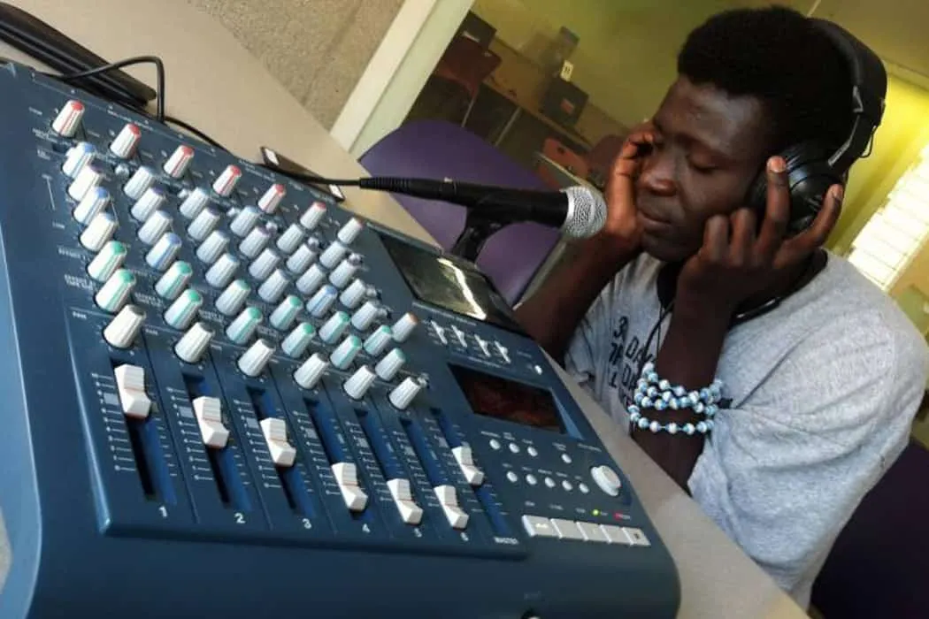 Professional DJ mixing music with audio console and headphones in studio setting, focusing on music production and sound engi