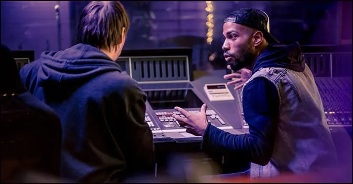 Recording studio session with two music producers collaborating on a track, using professional audio equipment and mixing con