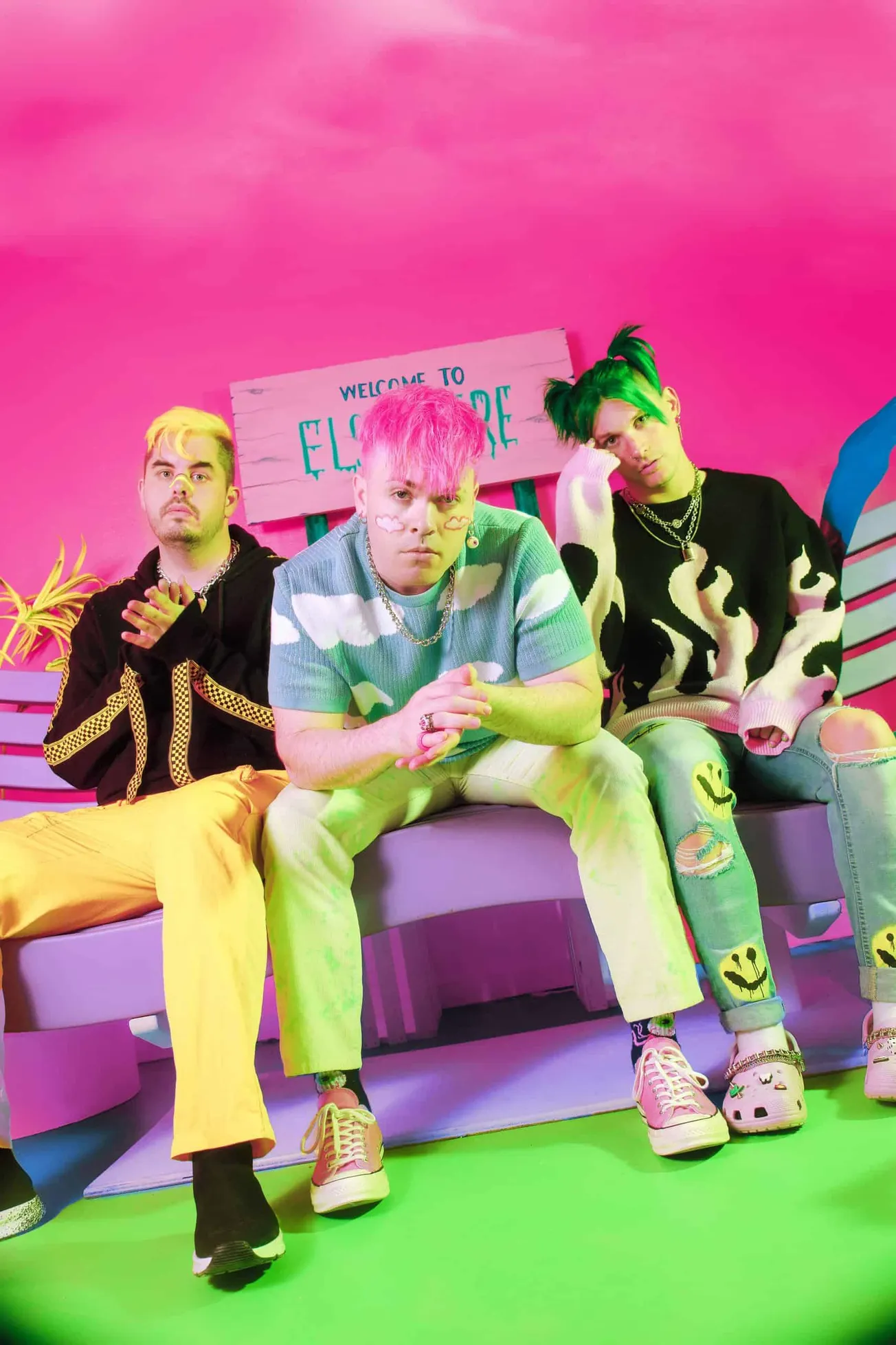 Colorful band members sitting on a bench with vibrant pink, green, and yellow background, showcasing trendy fashion, music in
