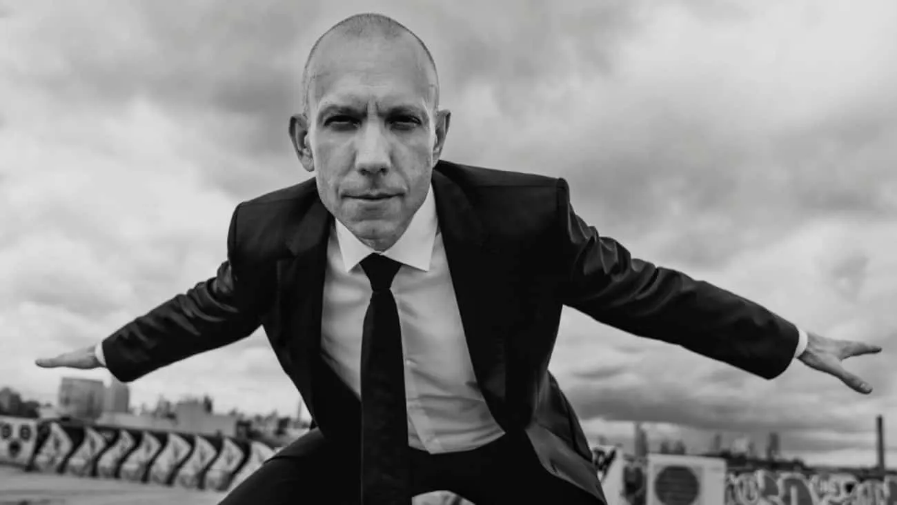 Focused man in business suit balancing on a rooftop with arms extended, black-and-white photo, symbolizing control, balance,