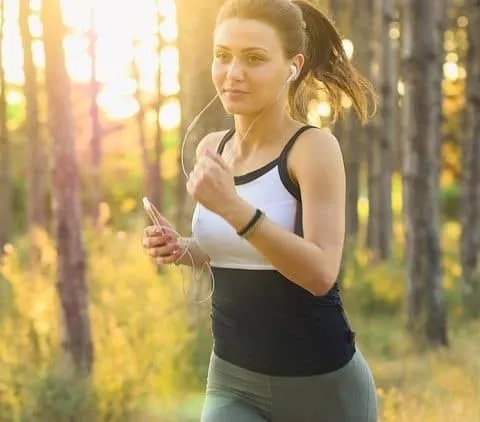 Young woman jogging outdoors in the forest during sunrise, enjoying fitness and wellness, representing active lifestyle inspi