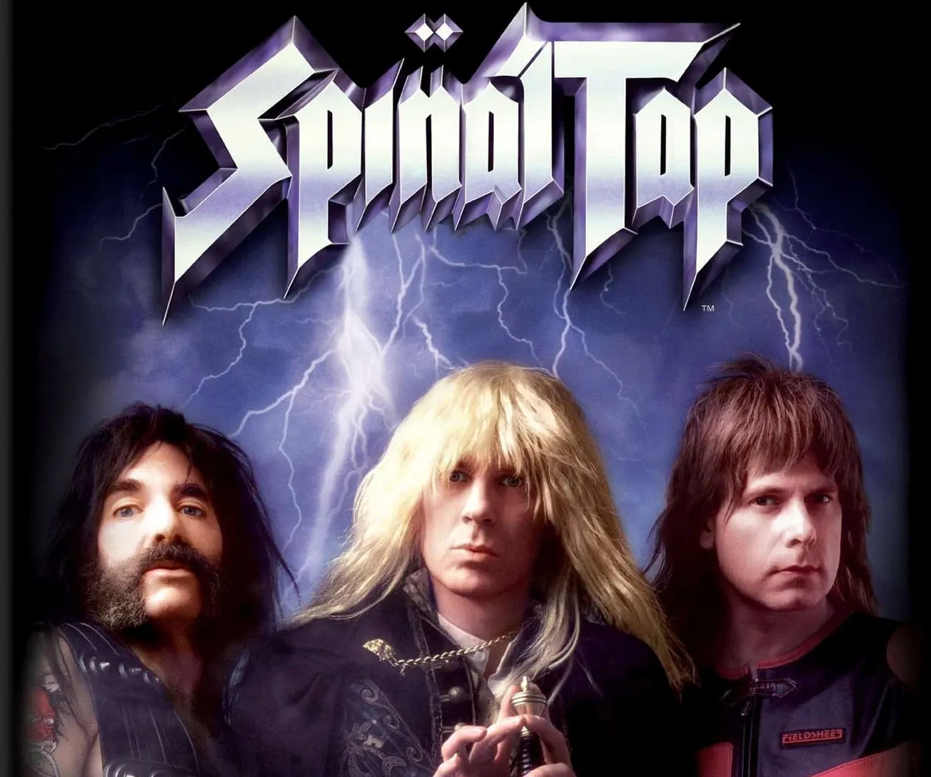 Metal band portrait featuring lead singer with long blonde hair, guitarist with dark hair and mustache, and bassist with brow