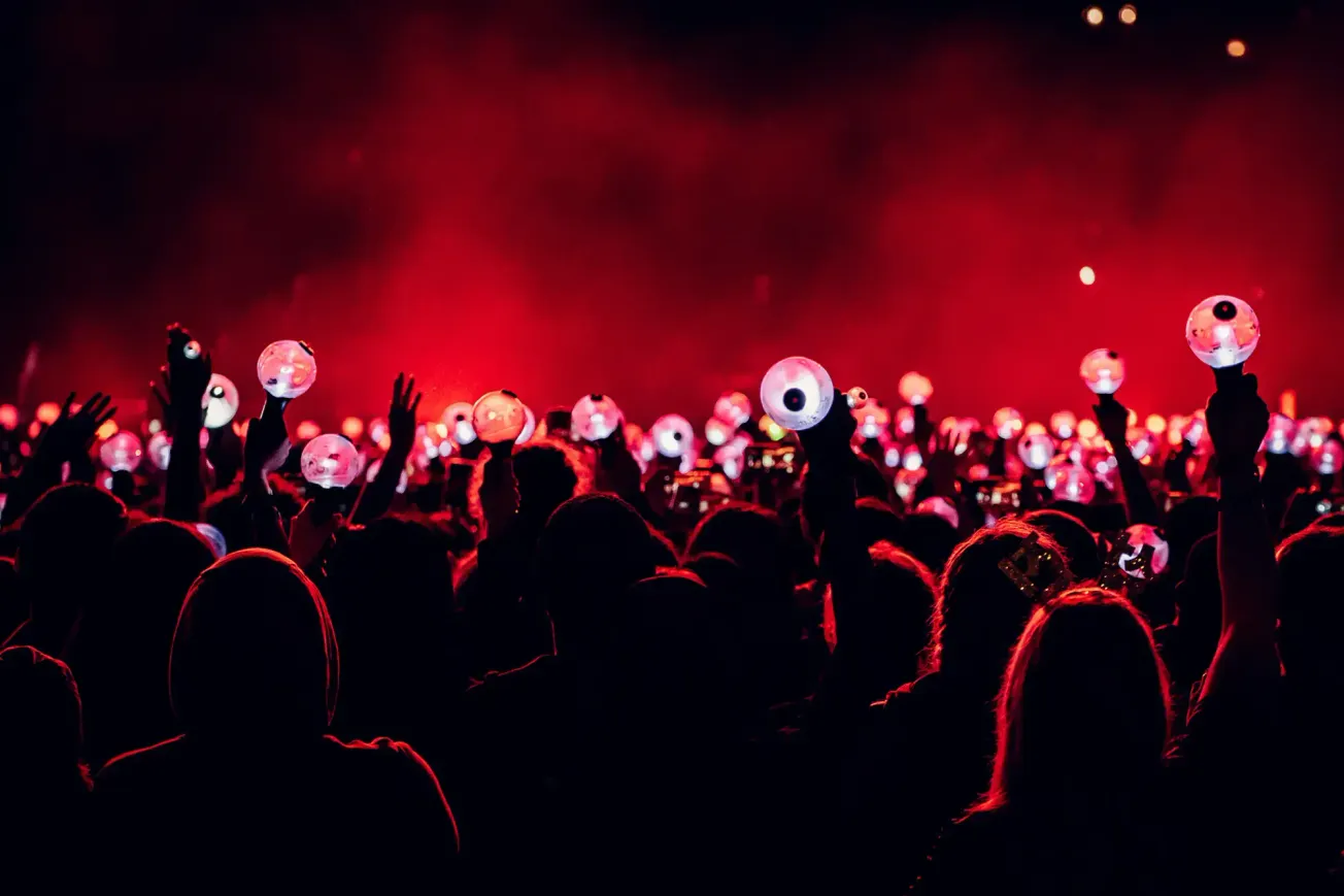 Glow-in-the-dark eye balloons at concert or music festival for crowd entertainment with vibrant red lighting, creating a dyna