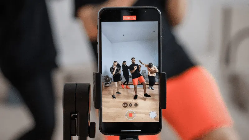 Dancing people recording a video on a smartphone at a dance class or rehearsal session.
