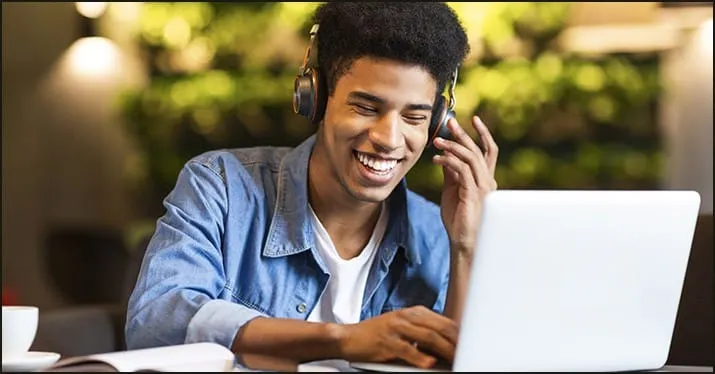 Young man enjoying music with headphones and laptop at a cafe, digital music, streaming, online entertainment, modern technol