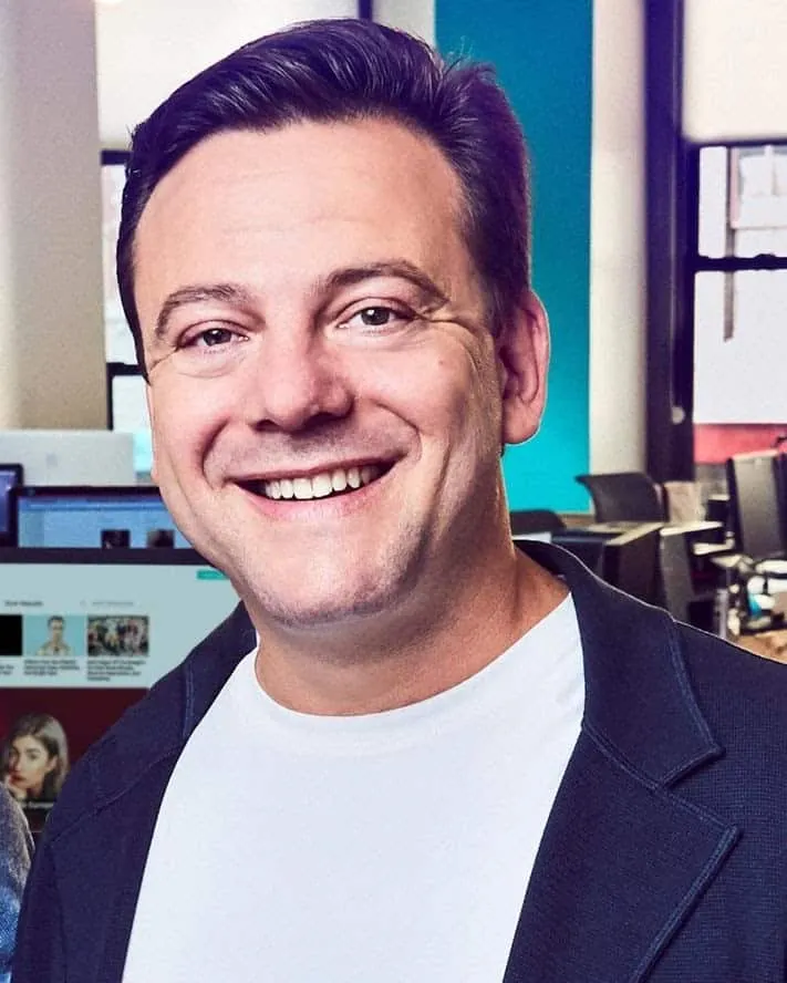 AI generated image of a smiling man in an office environment, promoting Hypebot's coverage of music industry news, digital ma