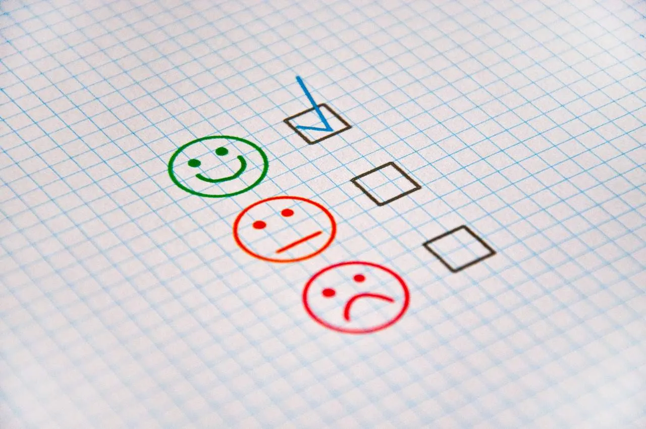 Happy face, sad face, and neutral face drawn on graph paper with checkboxes for customer feedback or satisfaction survey.