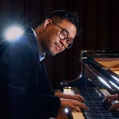 A professional musician playing piano in a dimly lit studio or concert hall at night, emphasizing musical creativity and tale