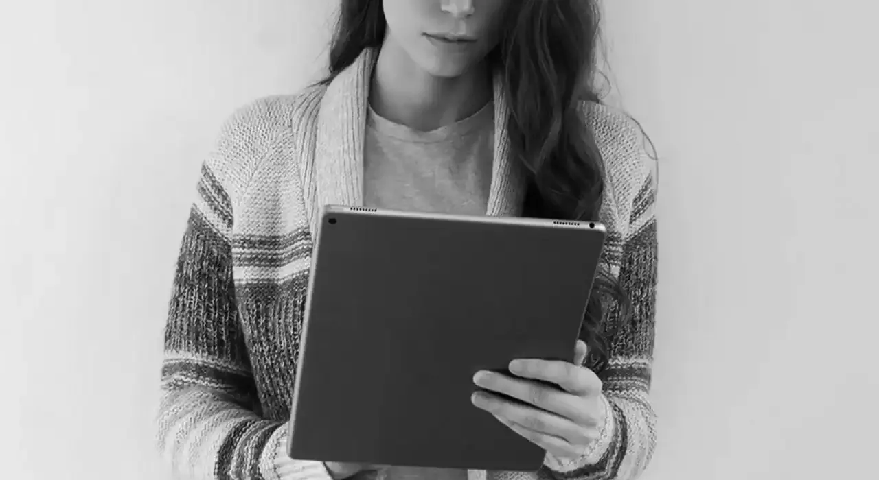 Woman using tablet device, digital media consumption, modern technology, casual attire, black and white photo.
