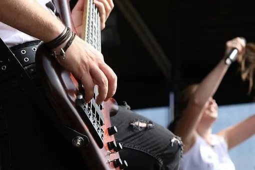 Guitarist playing electric guitar at live concert, focus on hand and instrument, music performance, rock band, stage lighting