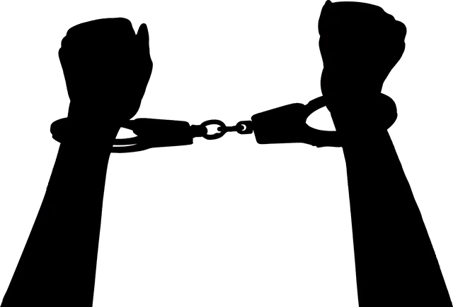 Handcuffed hands, symbolizing music industry challenges or artist restrictions, on a black silhouette background.