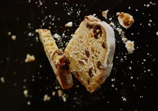 Chocolate chip cookie broken in half with crumbs on black background, close-up shot.