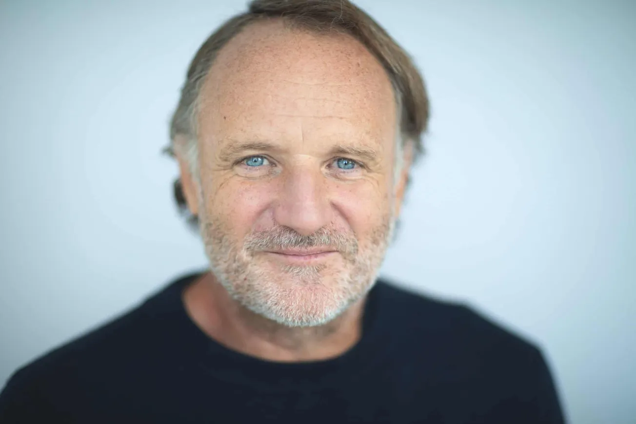 Senior man with gray hair and beard smiling, close-up portrait.