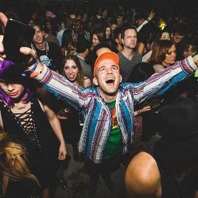Colorful party scene with excited young people enjoying music at a nightclub or music event.