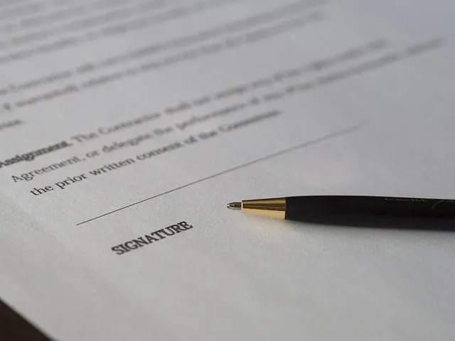 Signature on legal document with pen, close-up of paperwork for business or legal signing processes.