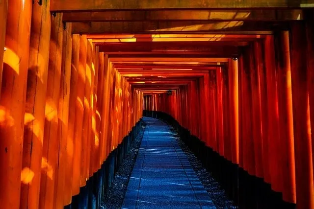 Vivid orange torii gates forming a pathway at Fushimi Inari Shrine in Japan, symbolizing spiritual transition and traditional
