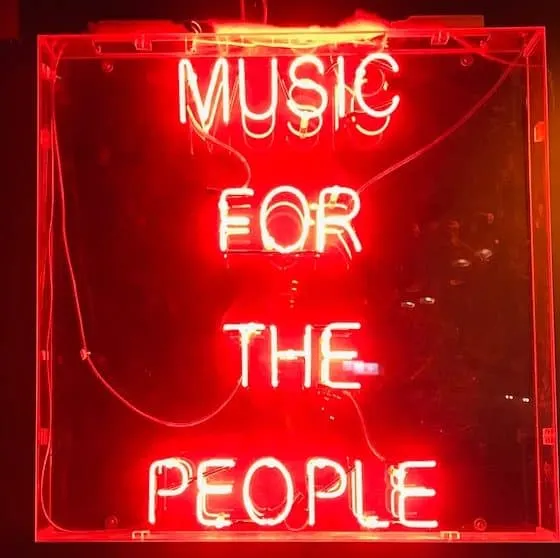 Neon sign reading "Music for the People" showcasing vibrant red lighting and urban music culture, perfect for promoting live