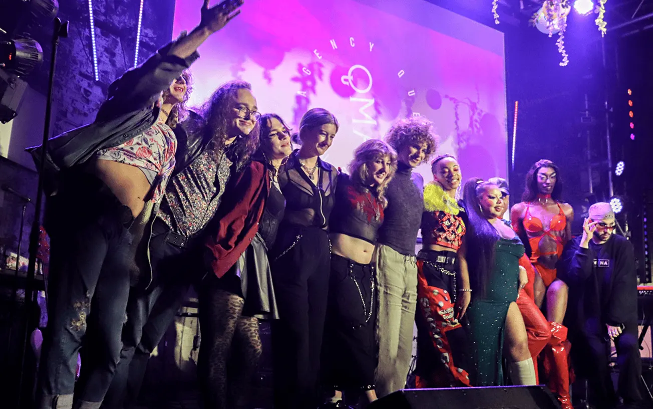 People on stage at a music event with vibrant lighting and diverse fashion styles for a hype music industry promotion.