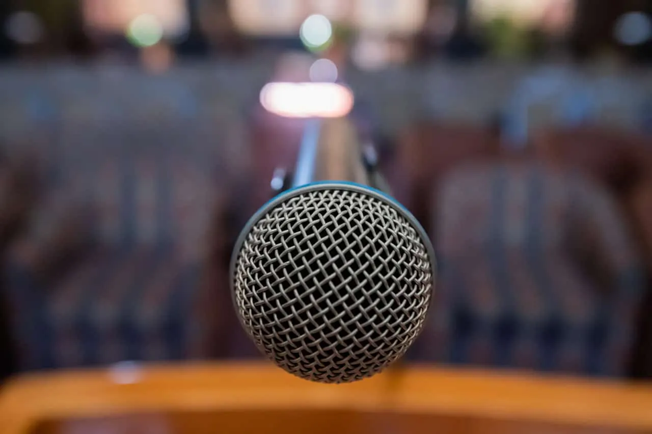 Microphone on a stage for live music or speech recording, with a blurred background of seating and lights, ideal for music in