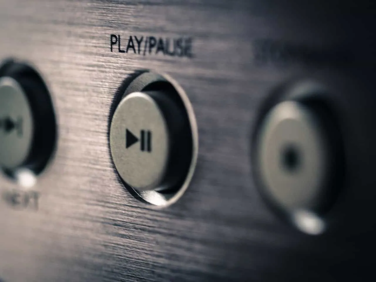 Button on audio equipment for play and pause functions, close-up shot.