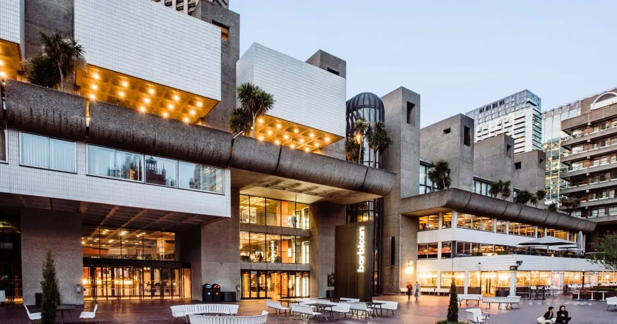 Modern urban building with glass windows, outdoor seating, and warm lighting, highlighting architecture and cityscape, perfec