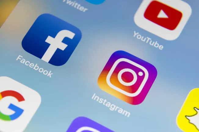 Facebook, Instagram, YouTube, social media icons on smartphone screen.