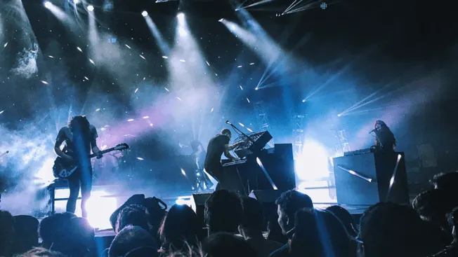 Live music performance featuring a band on stage with vibrant lights and an engaged audience at Hypebot concert event.