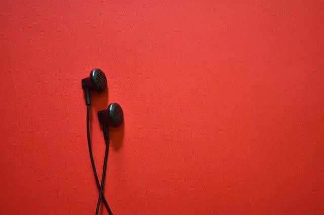 Black in-ear headphones on a vibrant red background, minimalistic music accessory, portable audio device, modern design for m