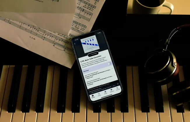 High-quality image of a music studio setup with sheet music, headphones, and a smartphone playing classical music, emphasizin