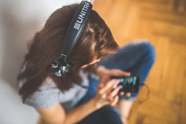Young woman with headphones listening to music and using a smartphone, representing digital music consumption and streaming t