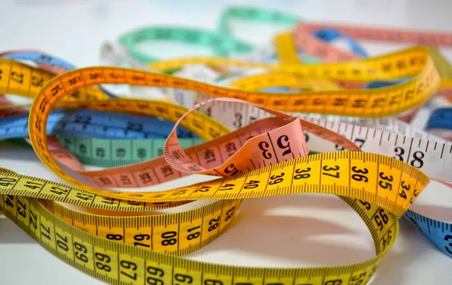 Colorful measuring tapes tangled in a heap, symbolizing measurement, tailoring, and fashion design concepts. Ideal for conten
