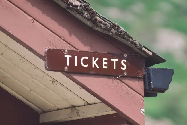 Tickets sign at an entrance or booth, indicating ticket sales or entry access, in a rustic setting with weathered wood.