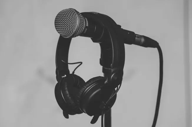 Microphone and headphones on a stand, studio recording equipment, professional audio setup for music, podcasting, or broadcas