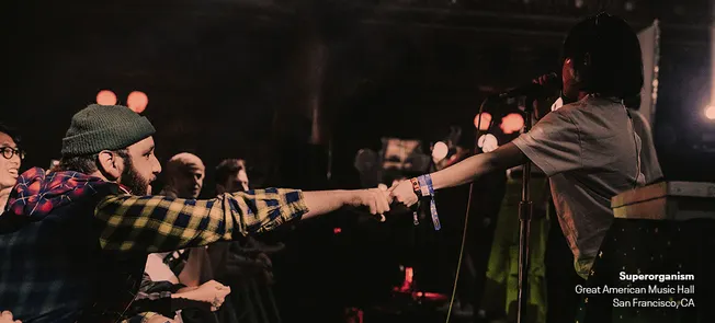 Fan sharing a concert moment at a live music event, audience interaction, music performance, San Francisco, CA, music venue,