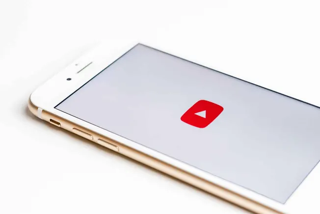 Mobile phone displaying the YouTube app icon on a clean white background.