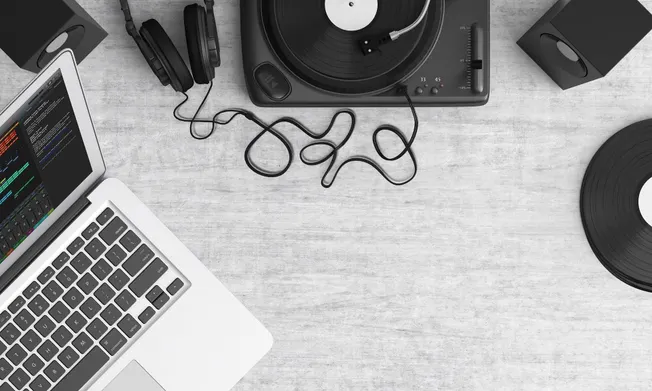 High-quality DJ equipment and music production setup on a modern desk, featuring a laptop, turntables, headphones, and vinyl