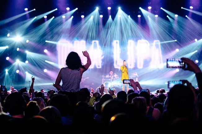 Dynamic concert audience at a music festival with vibrant stage lighting and performer on stage, capturing the energy and exc