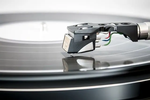 Tonearm of a vinyl turntable playing music, close-up shot with detailed needle and record surface.