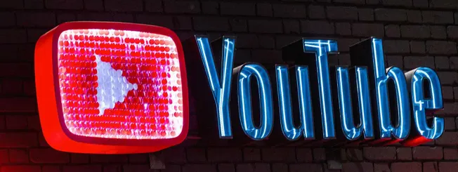 Red and blue neon YouTube logo sign with brick wall background, popular for digital content, social media branding, and onlin
