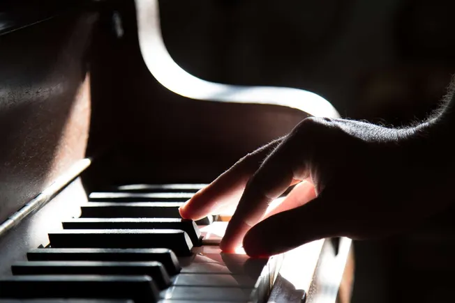Keyboard and hand playing piano, musical performance, close-up of fingers on keys, jazz or classical music, musician practici