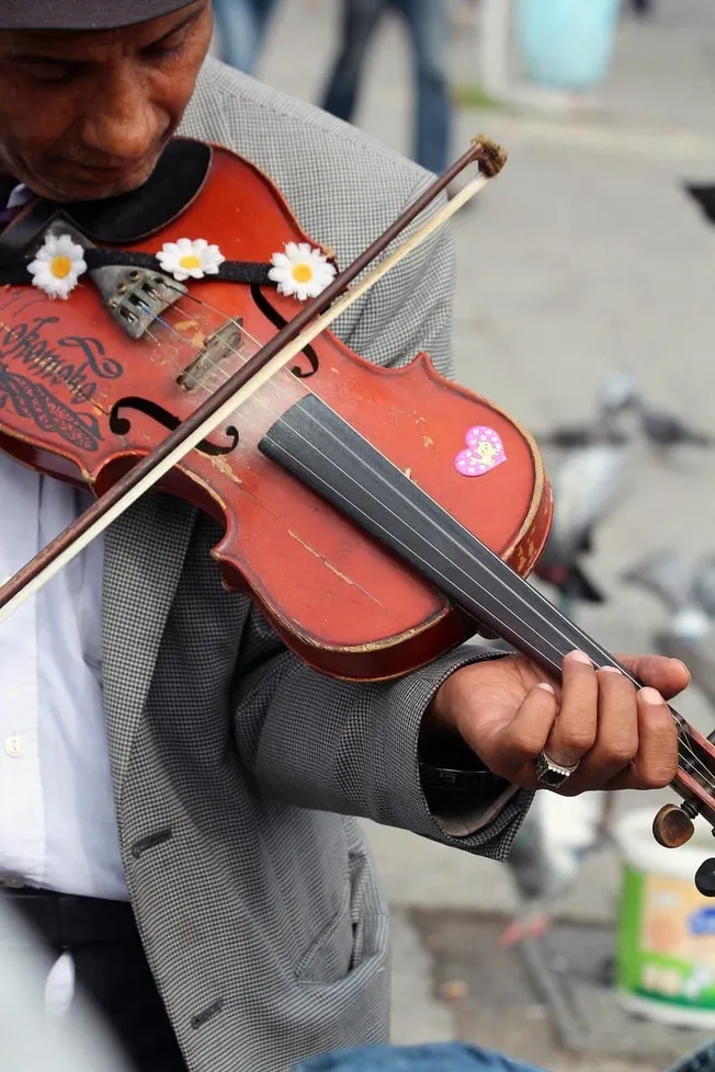 Vintage violin with floral decoration, being played by a street musician in an urban setting, showcasing lively street perfor