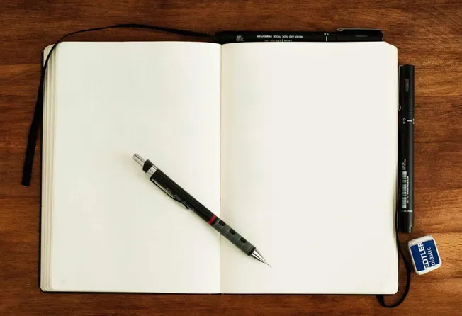 Open blank notebook with a black gel pen on wooden desk, featuring the Hypebot website context.