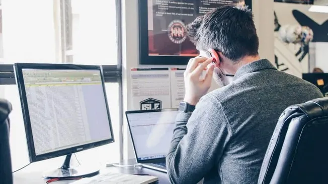 Data analyst working on multiple screens with music and media content on a computer, representing digital music industry tren