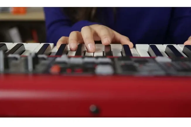 Keyboard playing hand on electronic music keyboard in studio, music production, digital instruments, music artist creating be