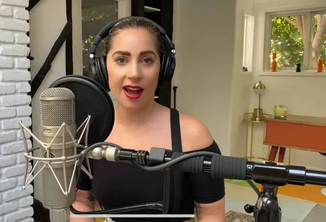 Professional female singer recording vocals with large microphone and headphones in a cozy home studio.