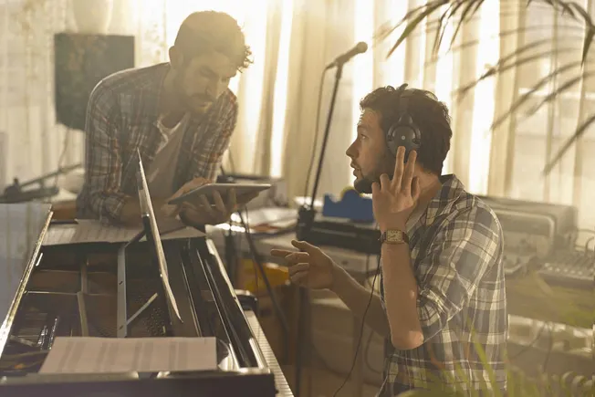 Creative music production session with artists collaborating in a home studio, focusing on songwriting, recording, and mixing