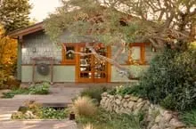 Charming single-story house with a landscaped garden, large windows, and a cozy outdoor seating area, perfect for enjoying na