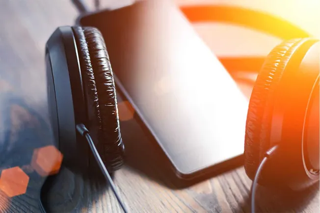 Wireless headphones resting on a smartphone, showcasing modern music listening technology and portable audio devices for cont