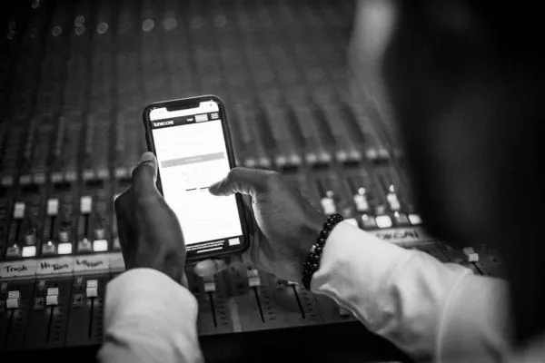 User posted an image of a person using a smartphone at a music production or audio mixing console. Based on the context and k